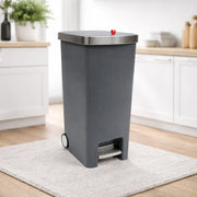Gray trash bin with a red button on a white rug in a kitchen setting