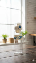 Clear water bottle with 'sports' text on a wooden table near a window.