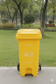 Yellow trash bin with recycling symbols in a park setting